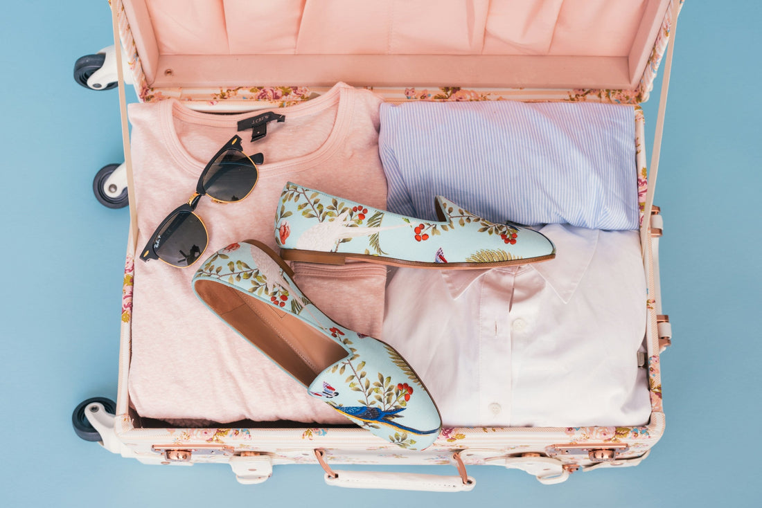 Clothing and a pair of shoes packed in a suitcase for a summer trip